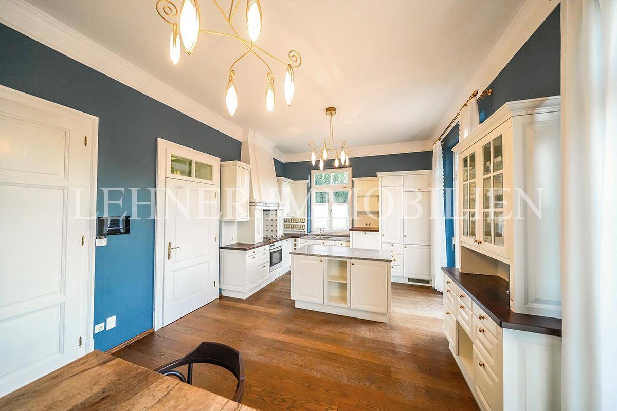 Geräumige Wohnküche mit traditionellen weißen Schränken, Kücheninsel und Essbereich.