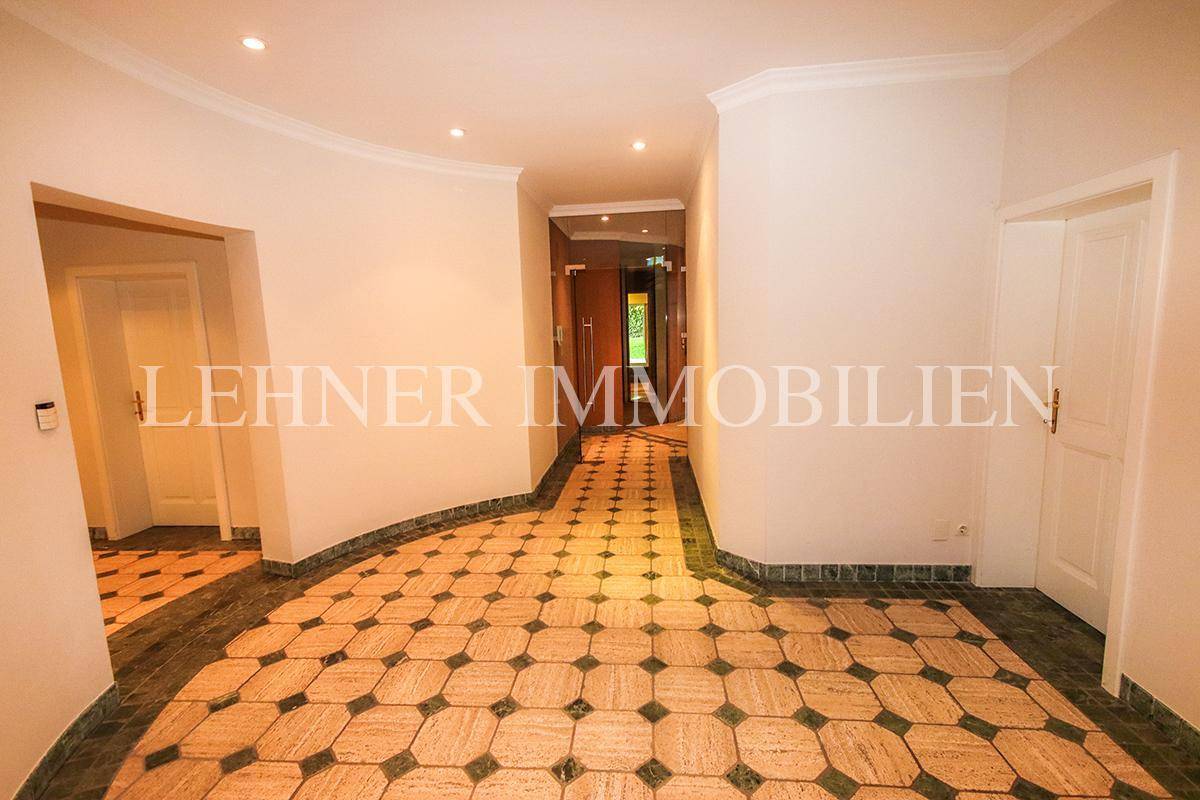 Heller Flur im Untergeschoss mit gemustertem Fliesenboden und indirekter Beleuchtung.