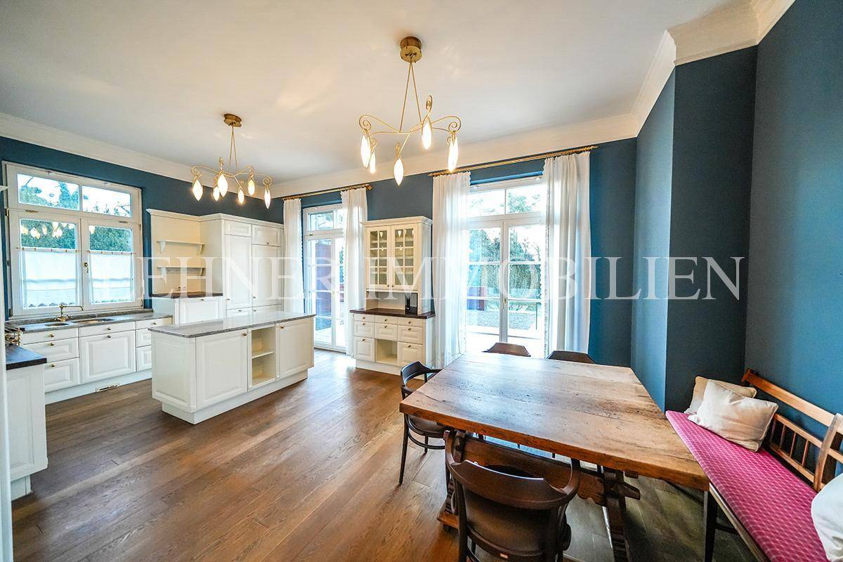 Helle Wohnküche mit weißen Schränken, Kücheninsel und großem Esstisch für gesellige Runden.