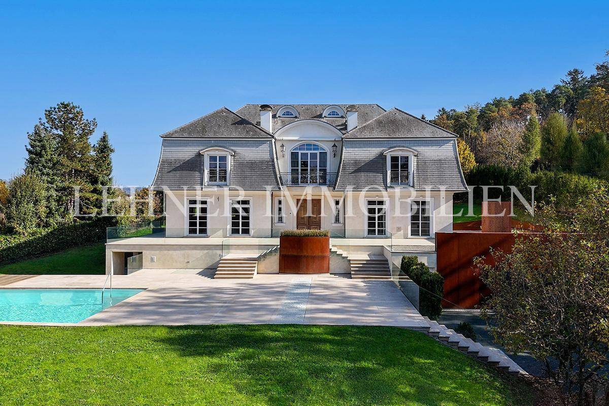 Elegante Villa mit klassischer Architektur, weitläufigem Garten und großzügiger Terrasse bei strahlendem Sonnenschein.
