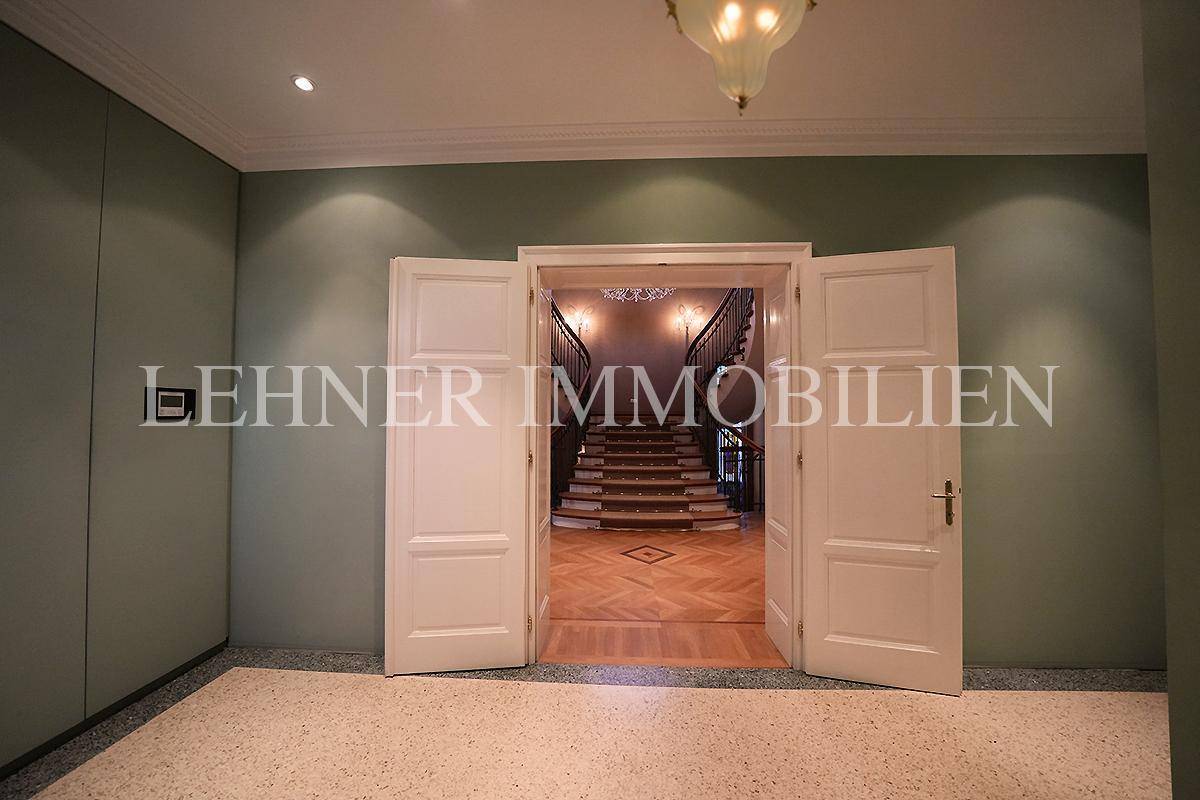 Heller Eingangsbereich mit Terrazzoboden und Blick auf das elegante Treppenhaus.