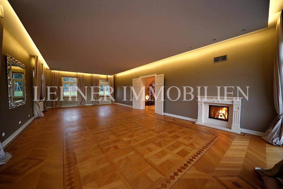 Elegantes Wohnzimmer mit Fischgrätparkett, Kamin und indirekter Beleuchtung für eine gemütliche Atmosphäre.