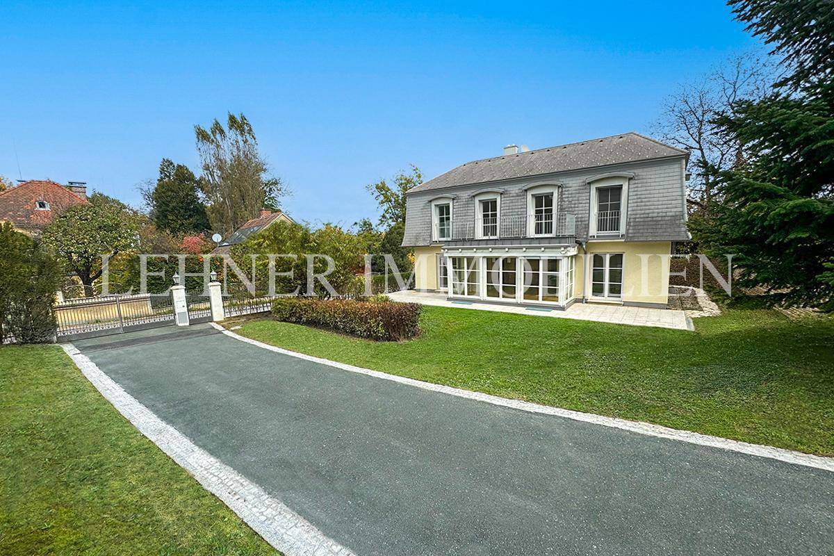 Rückansicht der Villa mit gepflegtem Garten, Auffahrt und klassischer Architektur.