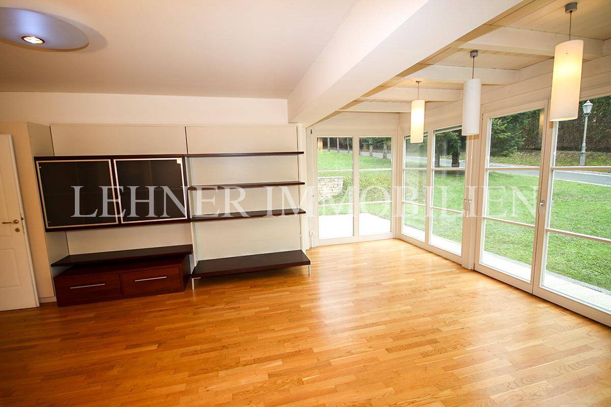 Helles Wohnzimmer mit Holzboden, großen Fenstern und Blick in den Garten.