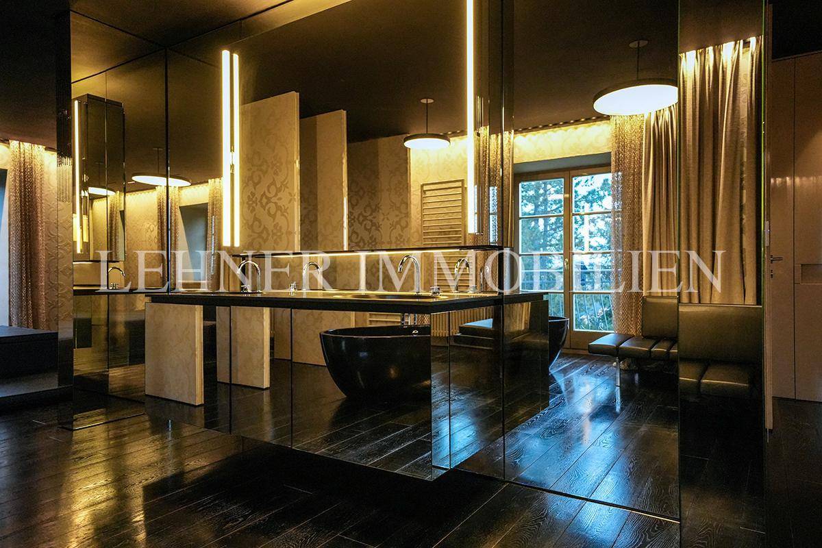 Exklusives Badezimmer mit dunklem Holzfußboden, freistehender Badewanne und großen Spiegelflächen.