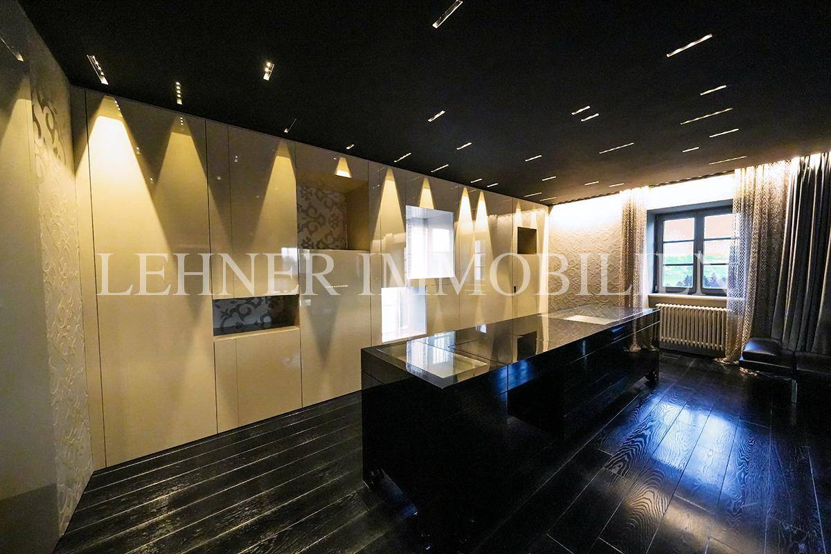 Luxuriöses Badezimmer mit dunklem Holzfußboden, glänzenden Oberflächen und indirekter Beleuchtung.