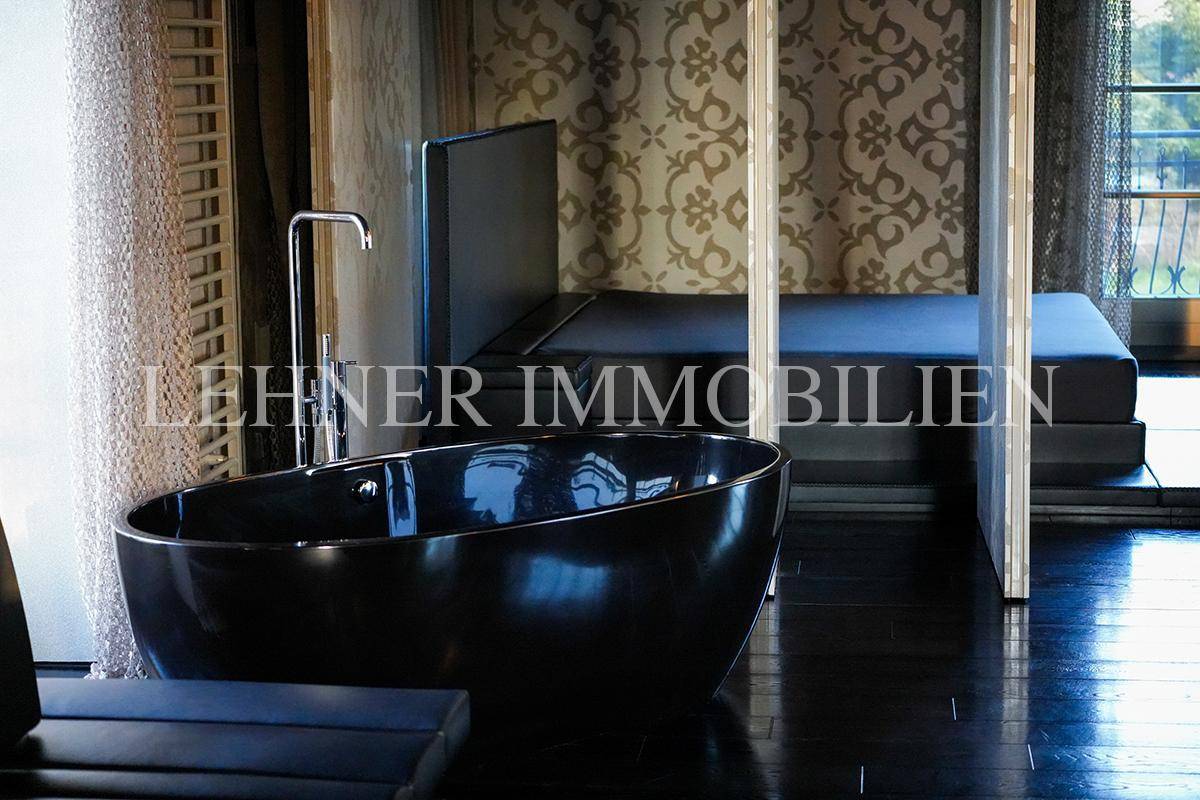 Freistehende Badewanne in einem luxuriösen Badezimmer mit dunklem Holzfußboden und elegantem Design.