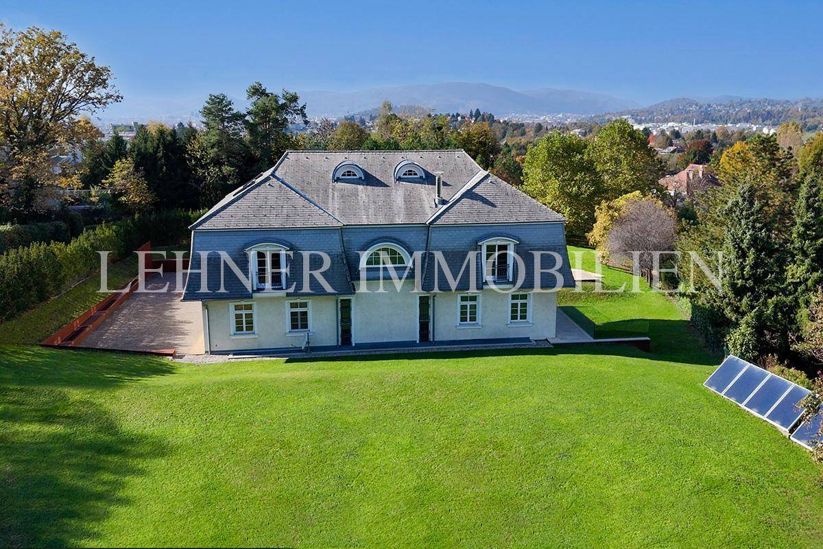 Rückansicht der Villa mit großem Garten, Rasenfläche und Photovoltaikanlage auf dem Grundstück.