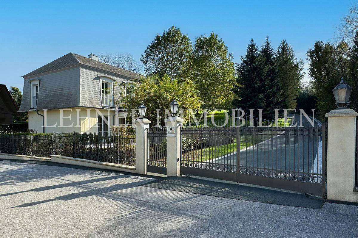 Repräsentatives Eingangstor zur Villa mit schmiedeeisernen Details und gepflegter Zufahrt.