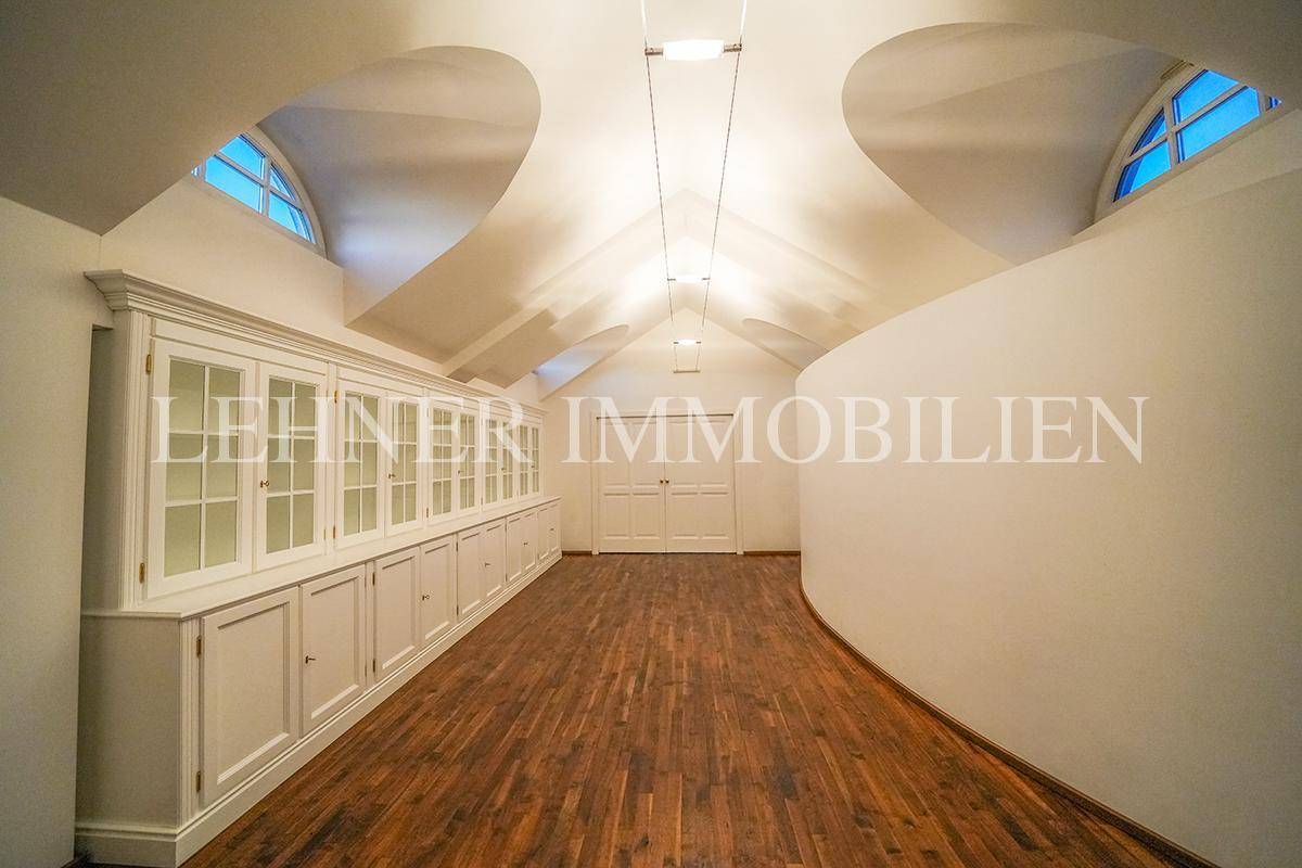 Heller Dachbodenraum mit Holzboden, Einbauschränken und gewölbter Decke.