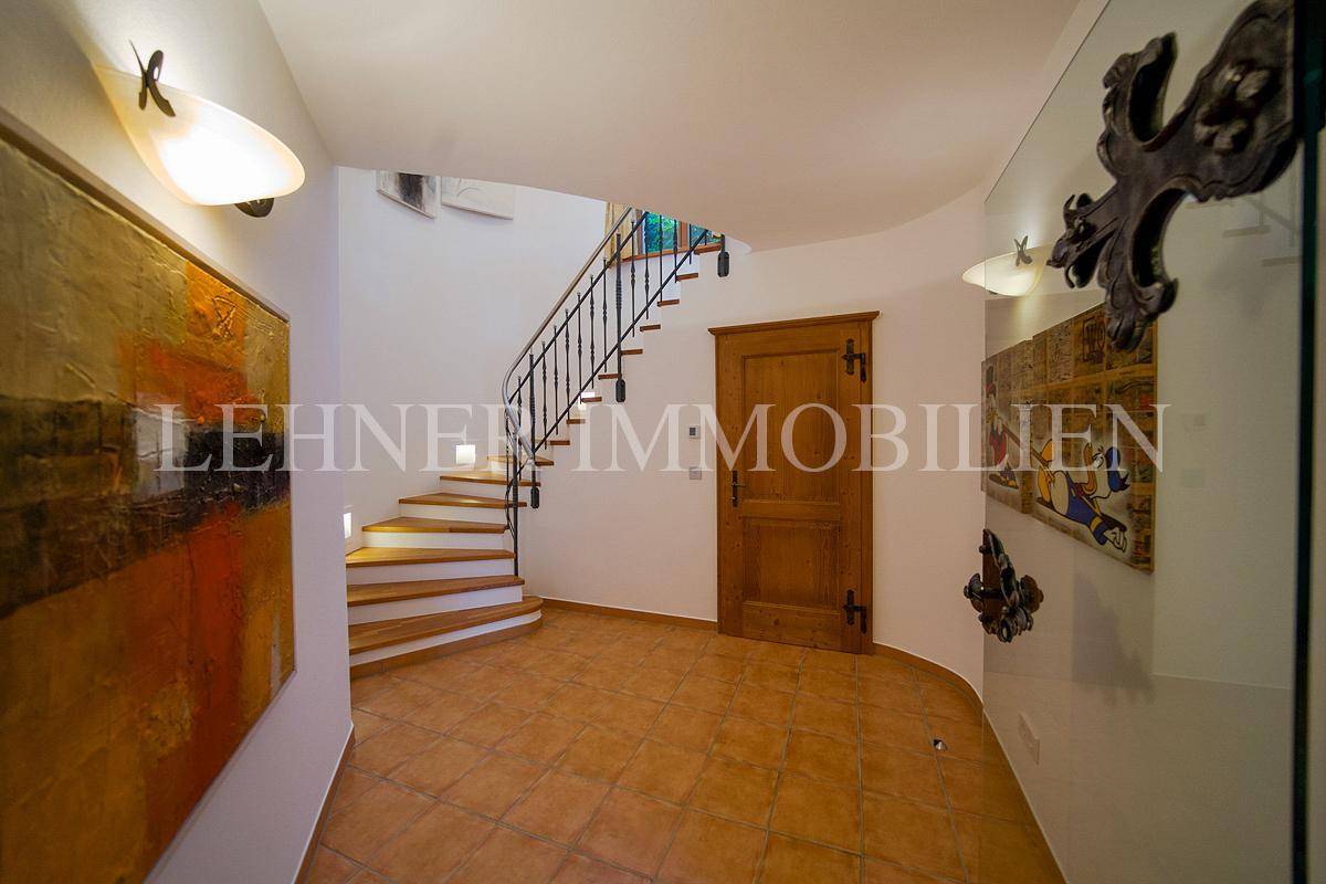 Heller Flur mit Terrakottafliesen, Holztür und Blick auf den Treppenaufgang.