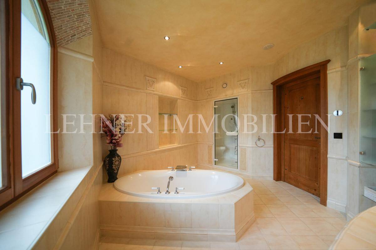 Geräumiges Badezimmer mit großer Badewanne, Duschkabine und beigen Fliesen.