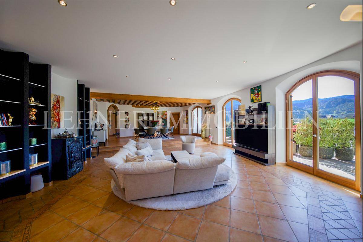 Heller Wohnbereich mit Terrakottafliesen, großen Fenstern und Blick auf die Terrasse.