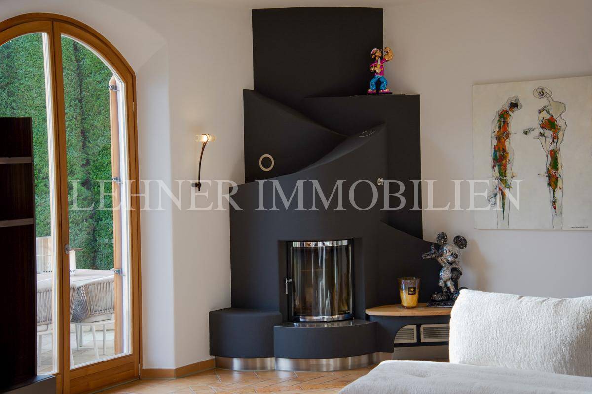 Moderner Kamin mit schwarzer Verkleidung und integriertem Holzofen im Wohnbereich.