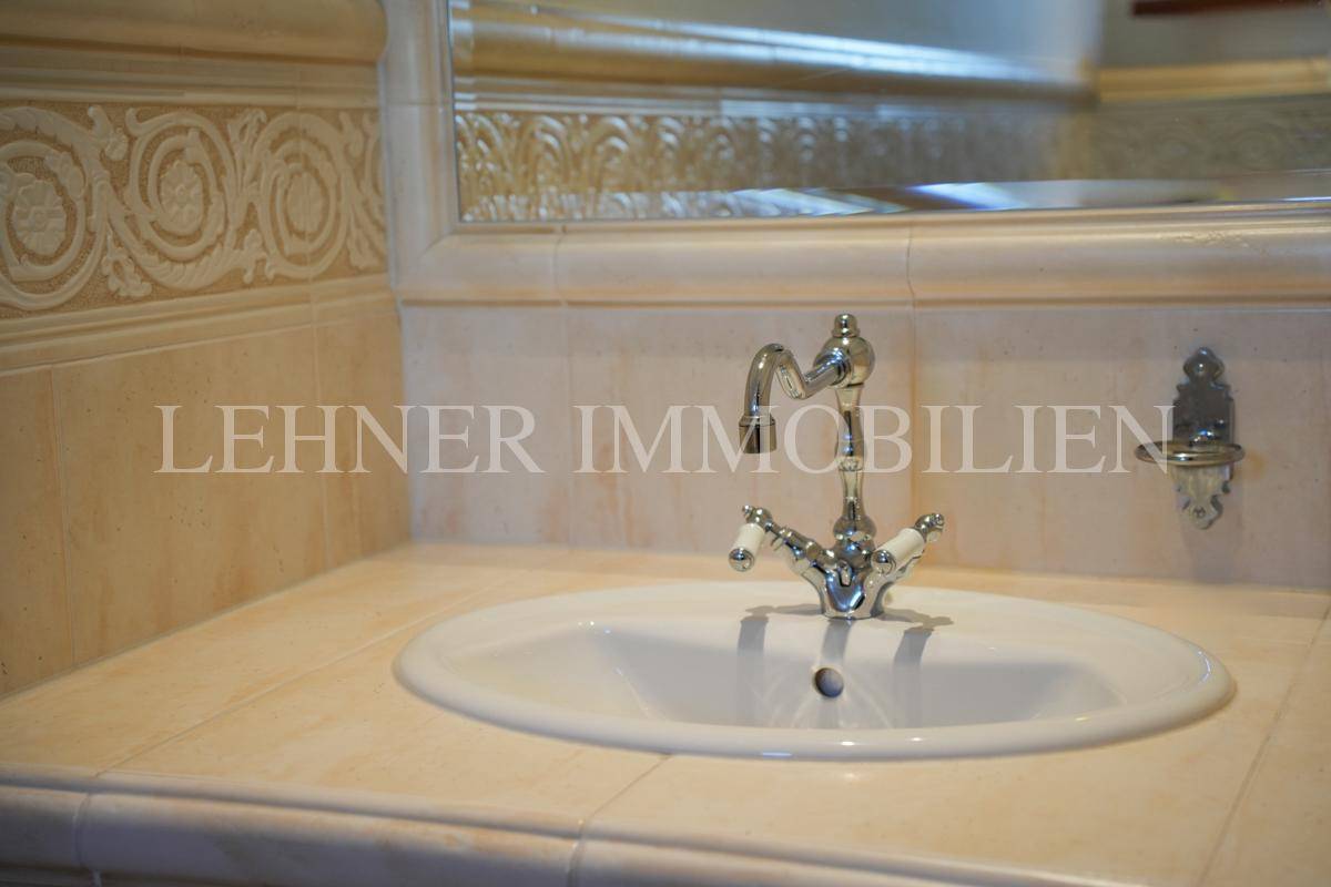 Detailansicht des Waschbeckens mit klassischen Armaturen und dekorativen Fliesen.