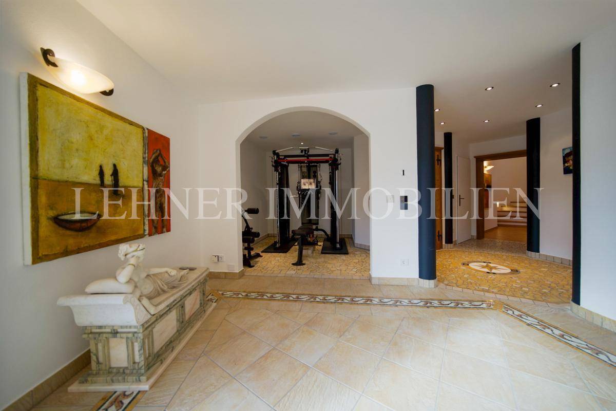 Fitnessbereich mit Trainingsgeräten und Fliesenboden, angrenzend an einen Entspannungsbereich.