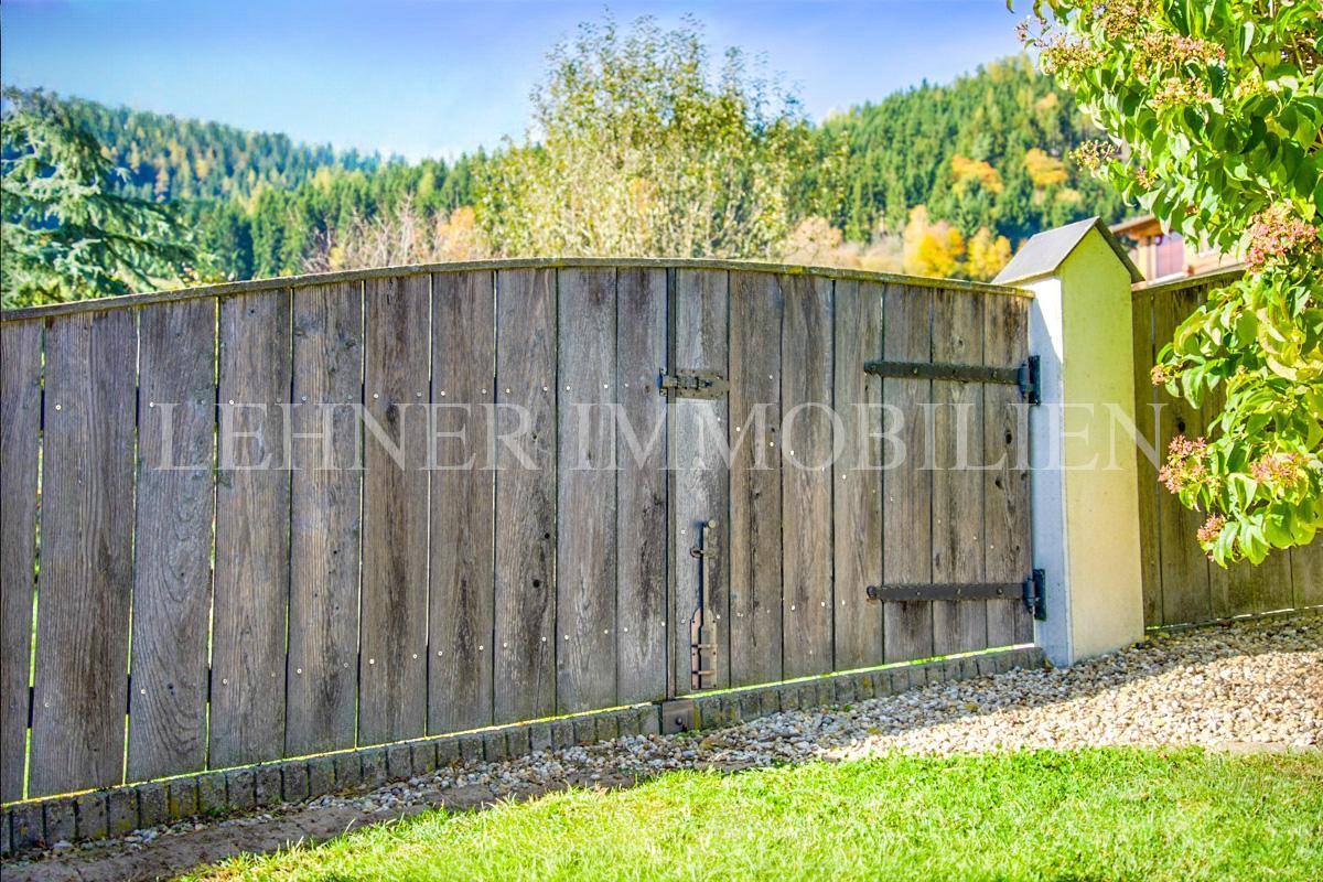 Rustikaler Holzzaun als Grundstücksgrenze in der ländlichen Umgebung.