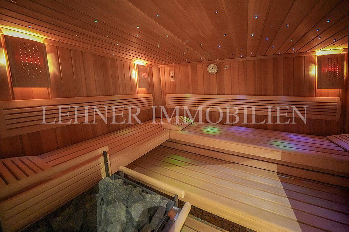 Geräumige Saunakabine aus Holz mit Bänken und farbiger Beleuchtung.