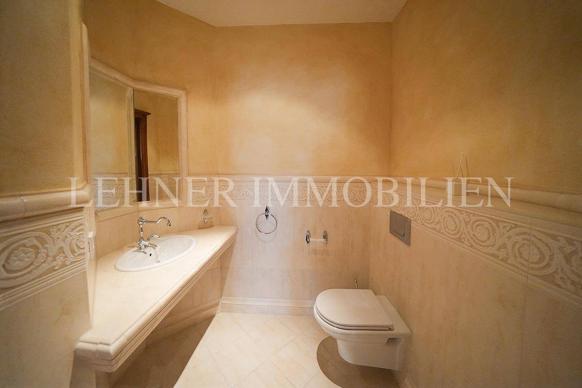 Gäste-WC mit Waschbecken, Spiegel und Wand-WC, in beigen Farbtönen.