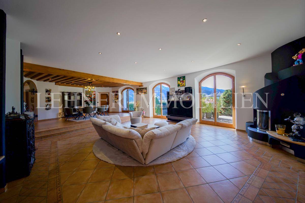 Heller Wohnbereich mit großem Sofa, Terrakottafliesen und modernem Kamin.