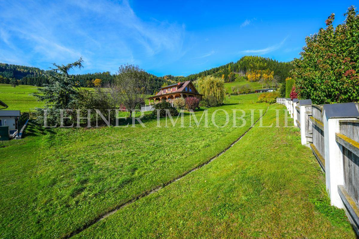 Weitläufige grüne Wiesen und Hügel mit einem weiteren Gebäude im Hintergrund.