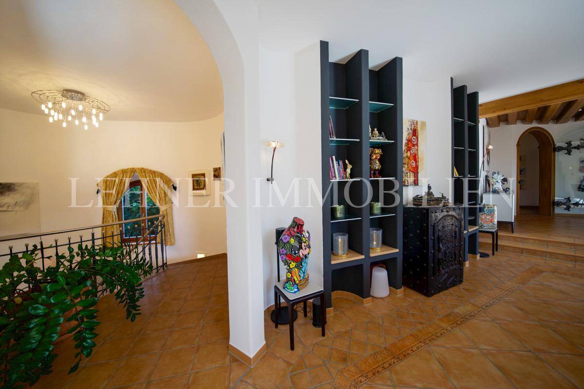 Heller Flur mit Terrakottafliesen, Bücherregalen und Blick auf den Treppenaufgang.