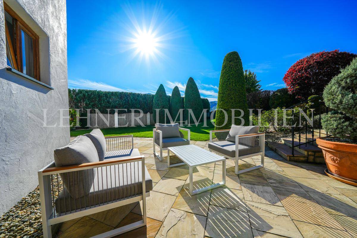 Sonniger Terrassenbereich mit modernen Sitzmöbeln und Blick auf die gepflegte Gartenanlage.