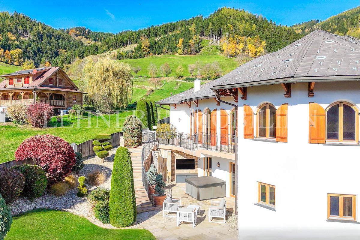 Seitenansicht der Villa mit Terrasse, Whirlpool und gepflegtem Garten in ländlicher Umgebung.