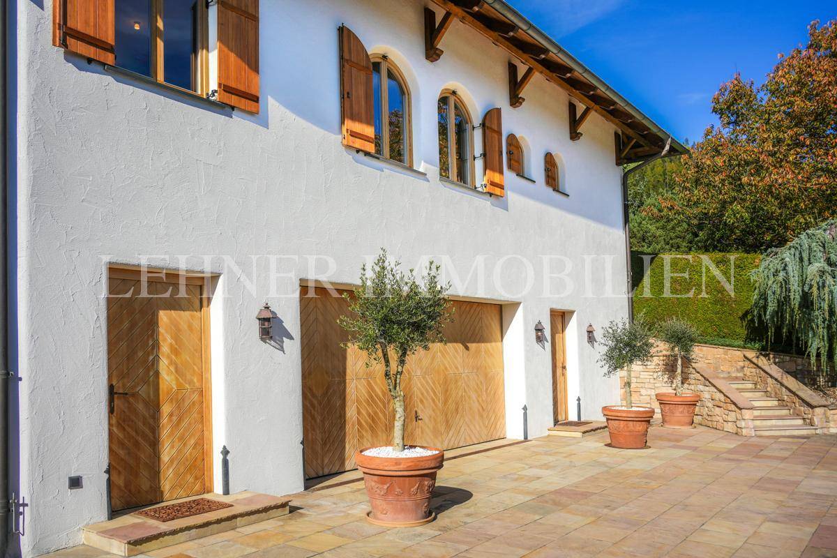 Garagen- und Eingangsbereich der Villa mit Holztoren und mediterranen Topfpflanzen.