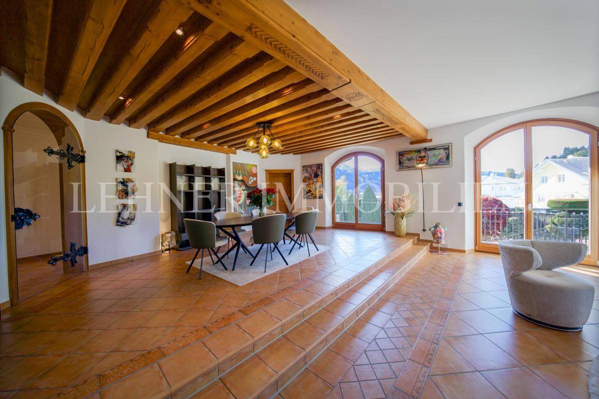 Offener Wohn- und Essbereich mit Terrakottafliesen, Holzbalkendecke und Stufen zum Wohnbereich.