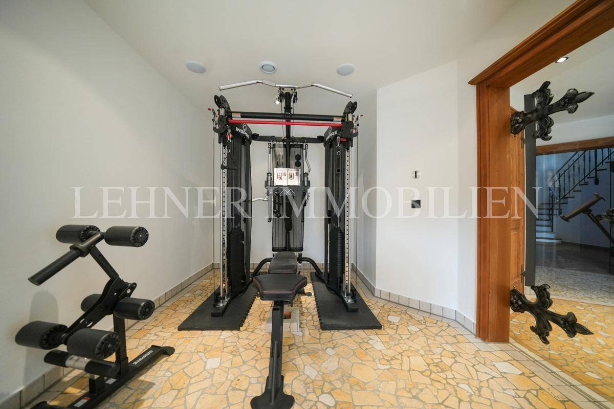 Moderner Fitnessbereich mit Krafttrainingsgerät und Fliesenboden.