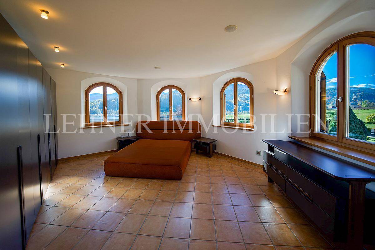 Geräumiges Schlafzimmer mit Terrakottafliesen, großem Bett und Fenstern mit weitem Blick.