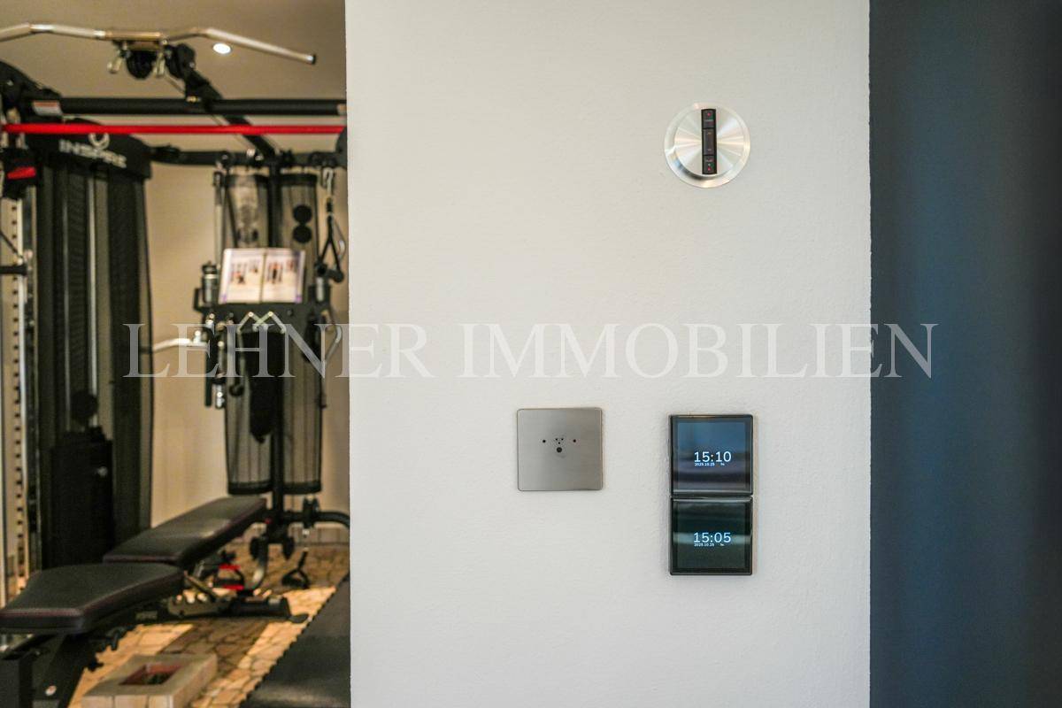 Detailansicht moderner Smart-Home-Steuerungselemente an der Wand im Fitnessbereich.