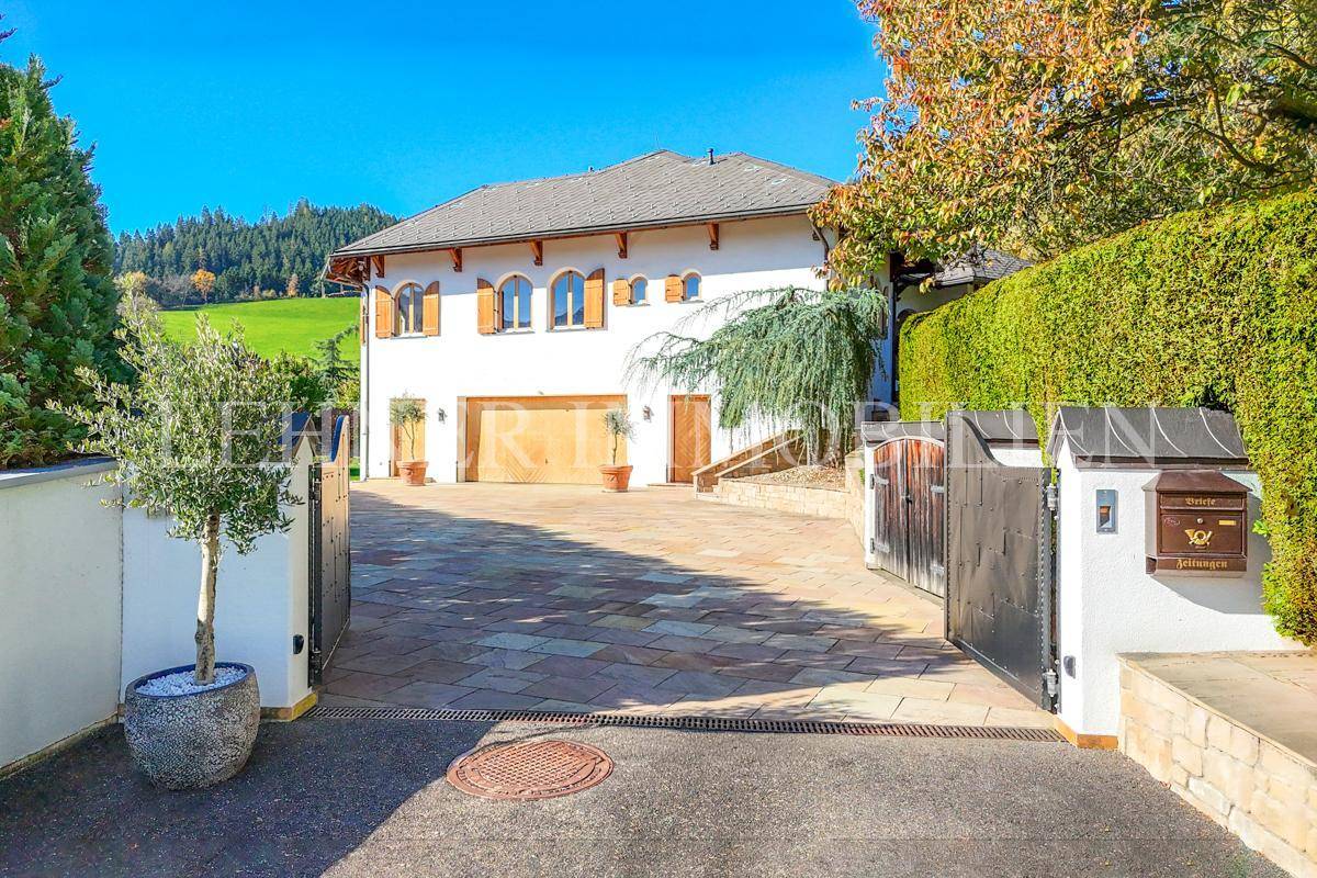 Eingangsbereich der Villa mit großem Tor, gepflasterter Auffahrt und mediterranen Pflanzen.