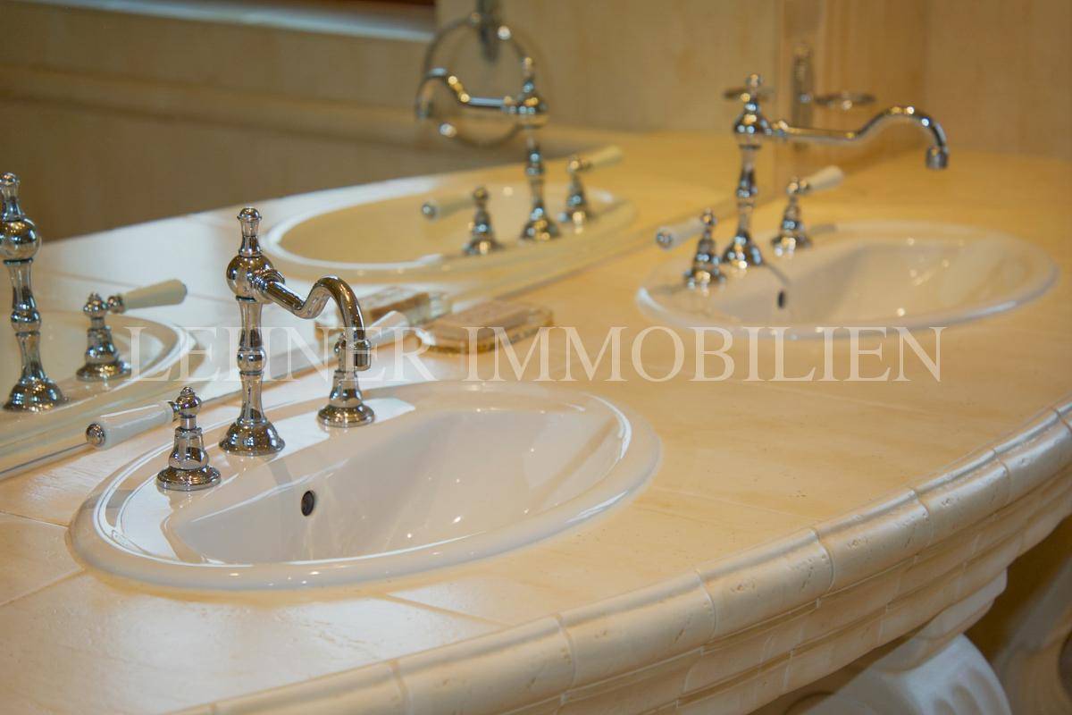 Detailansicht des Doppelwaschbeckens mit klassischen Armaturen und beiger Arbeitsplatte.