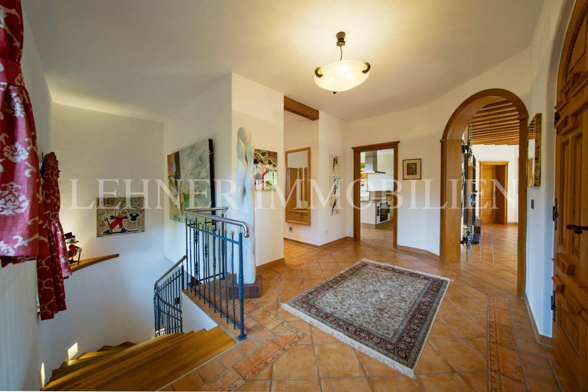 Geräumiger Eingangsbereich mit Terrakottafliesen, Treppenaufgang und Blick in die Küche.