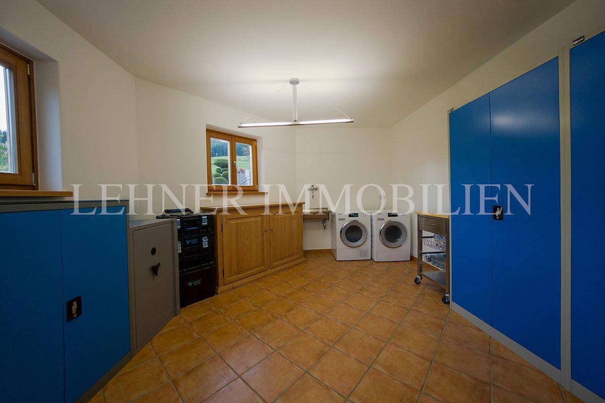 Geräumiger Hauswirtschaftsraum mit Waschmaschinen, Spüle und blauen Schränken.