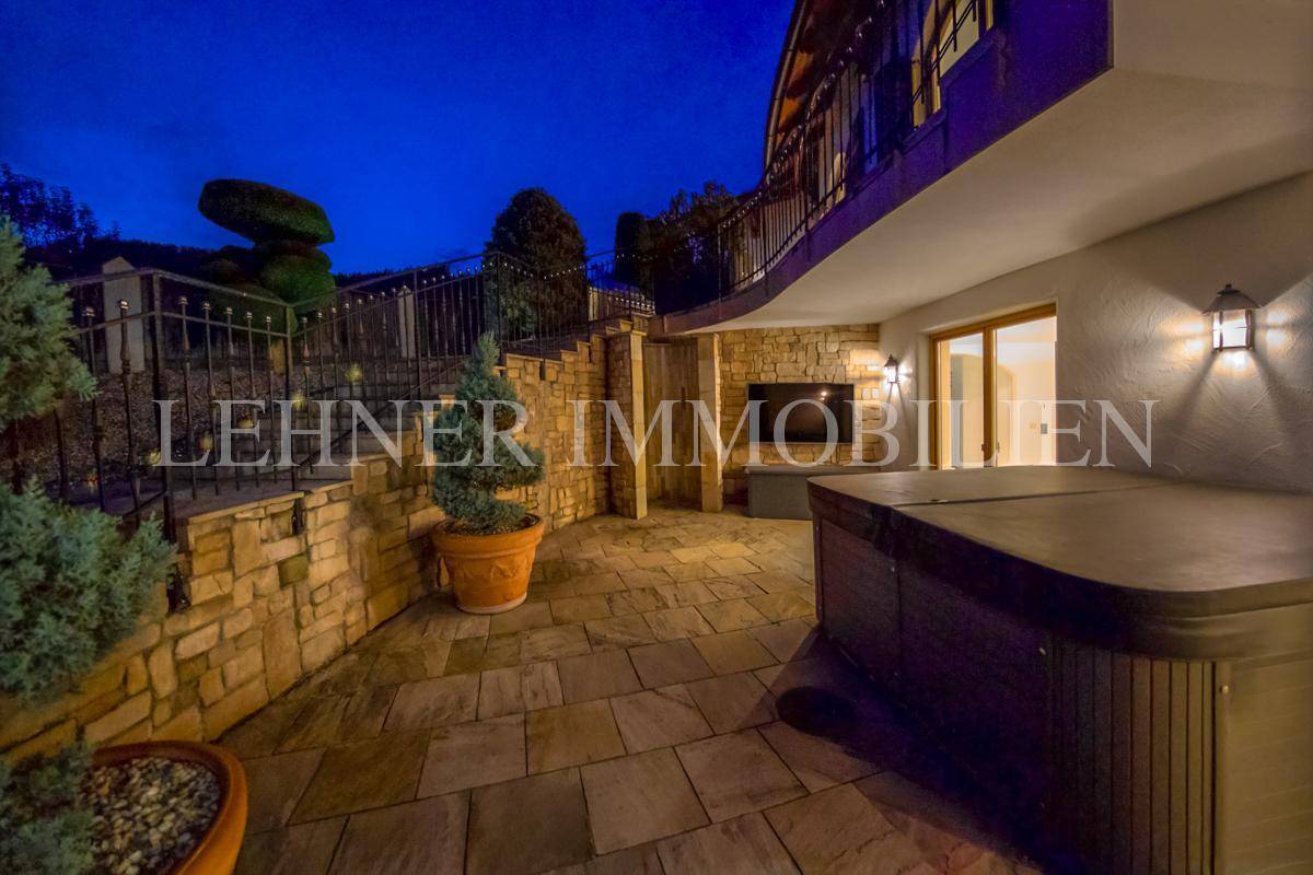 Gemütlicher Terrassenbereich mit Natursteinwand, Whirlpool und indirekter Beleuchtung.