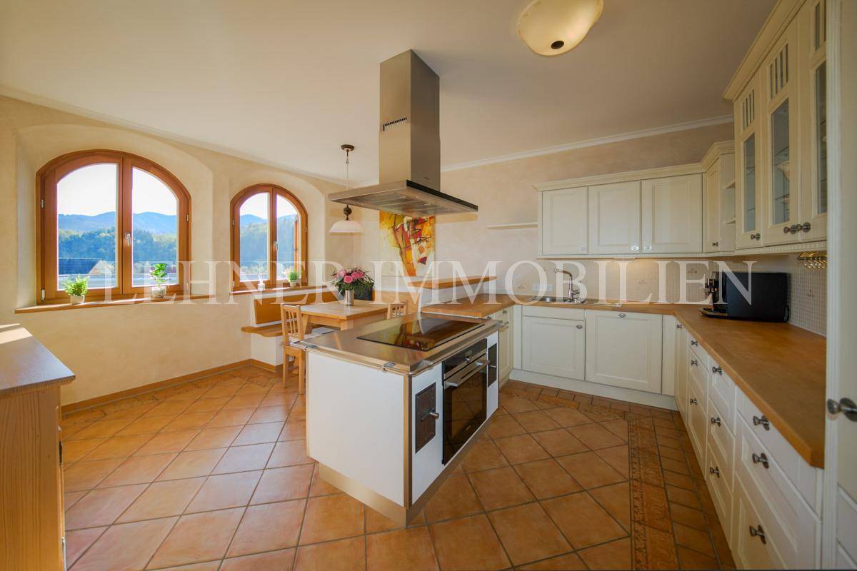 Helle Einbauküche mit Kochinsel, Essbereich und großen Fenstern mit Bergblick.