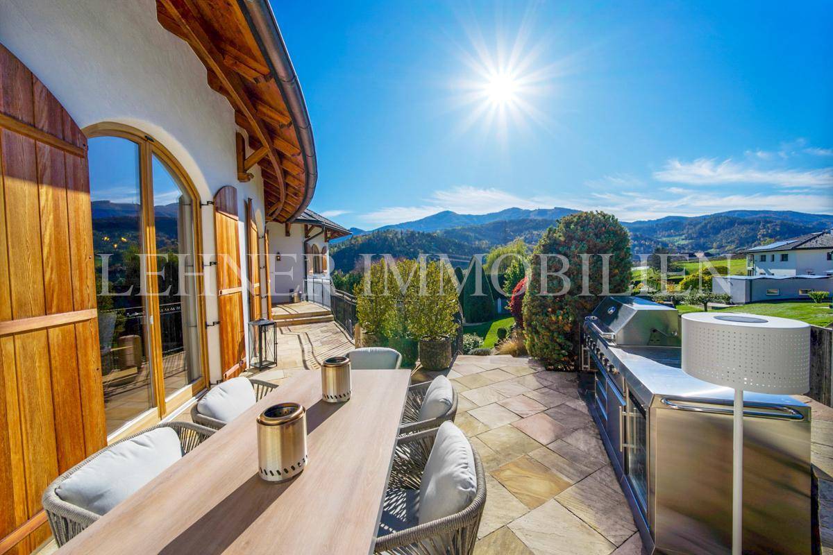 Sonniger Terrassenbereich mit Esstisch, Außenküche und weitem Blick auf die Berge.