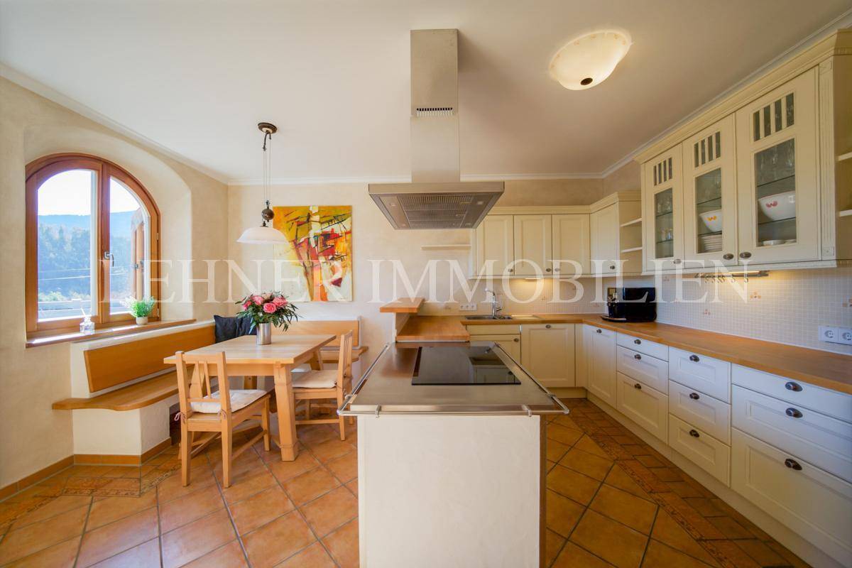 Helle Einbauküche mit Kochinsel, Essbereich und Terrakottafliesen, mit Blick ins Grüne.