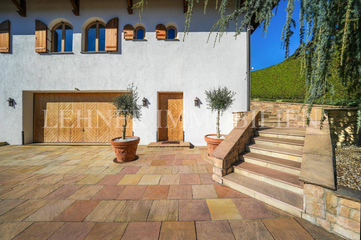 Garagen- und Eingangsbereich mit Holztoren, gepflastertem Vorplatz und Steintreppe.