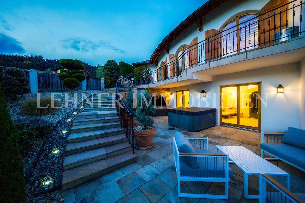 Geräumige Terrasse mit modernen Outdoor-Möbeln und Whirlpool, umgeben von gepflegten Pflanzen.