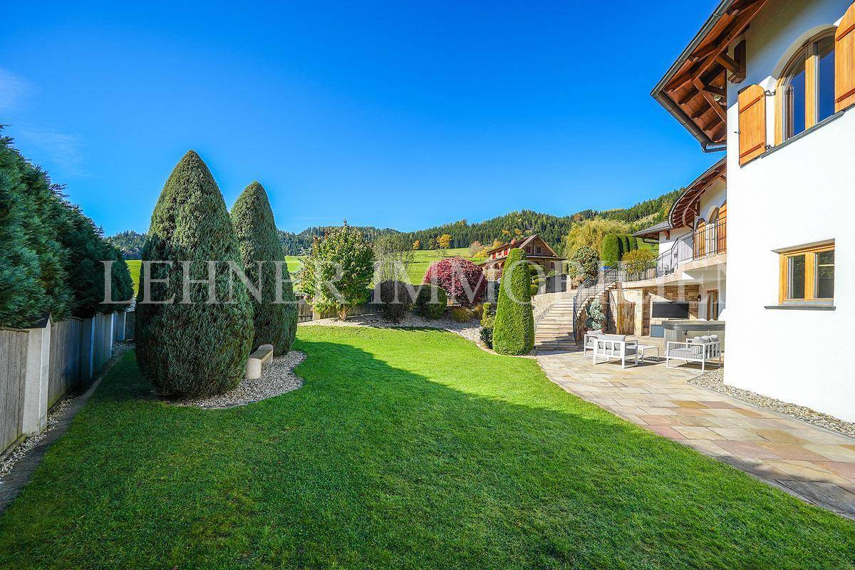 Weitläufiger Rasenbereich mit gepflegten Hecken und Bäumen, angrenzend an die Villa.