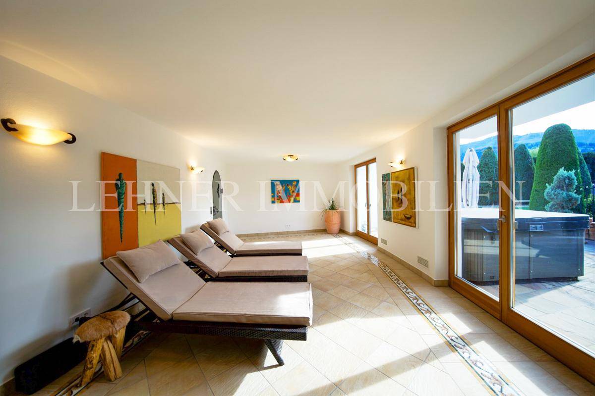 Entspannungsbereich mit Liegen, Fliesenboden und Blick auf den Whirlpool im Freien.