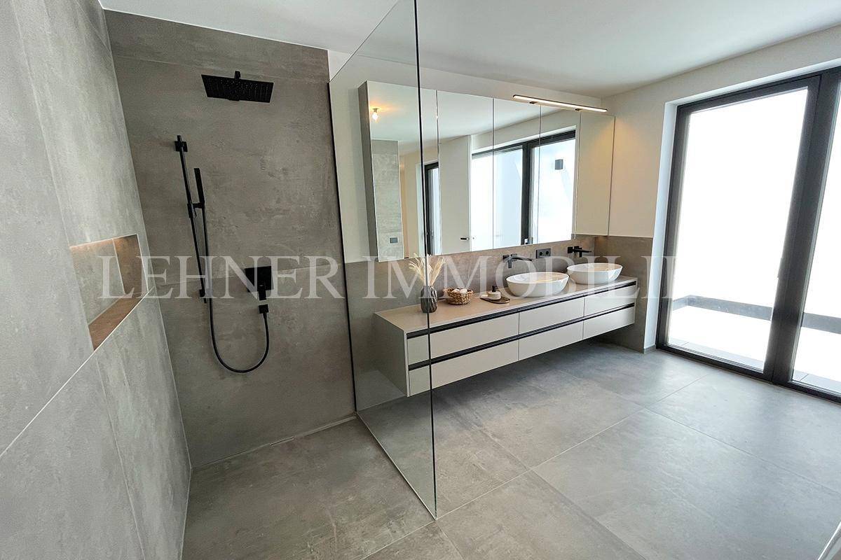 Modernes Badezimmer mit begehbarer Dusche, Doppelwaschbecken und großem Spiegelschrank.