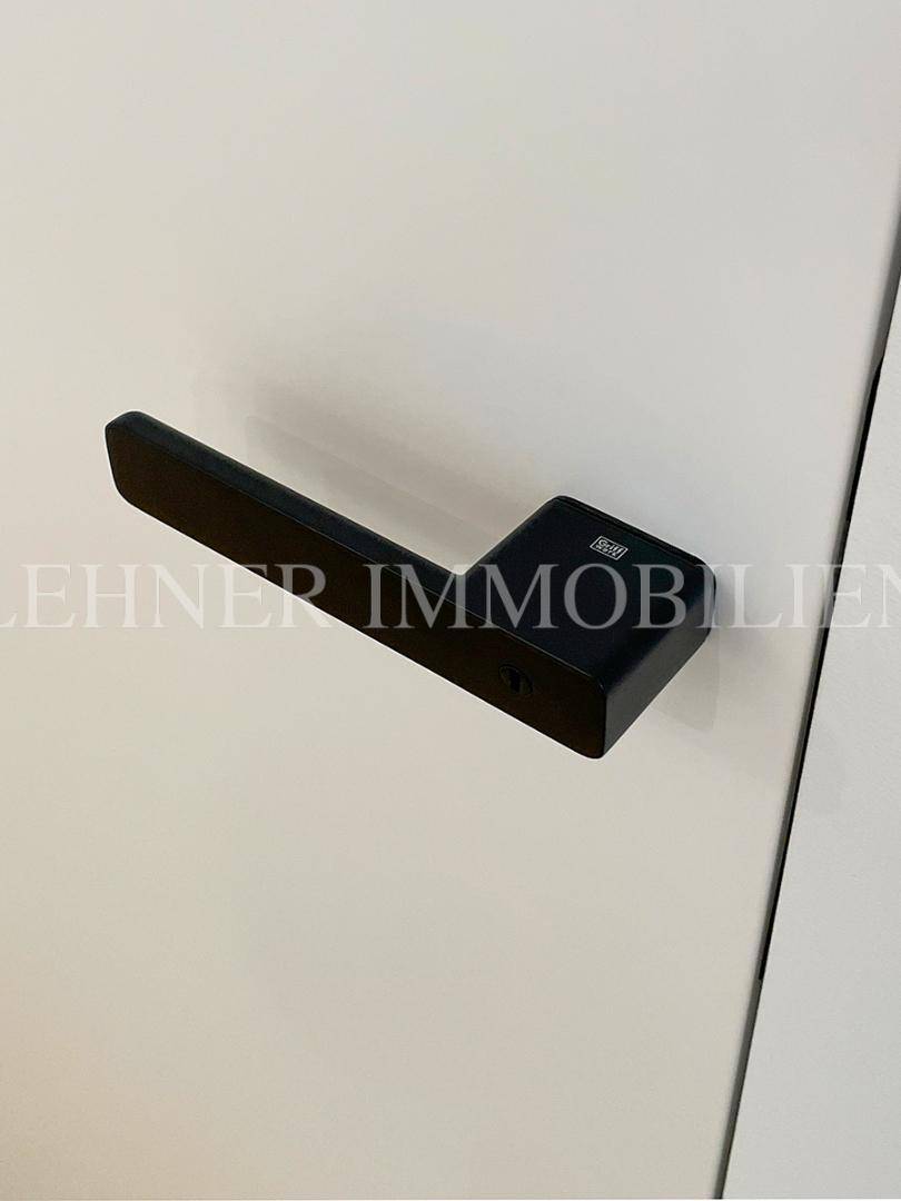 Detailaufnahme eines modernen schwarzen Türgriffs an einer weißen Tür.