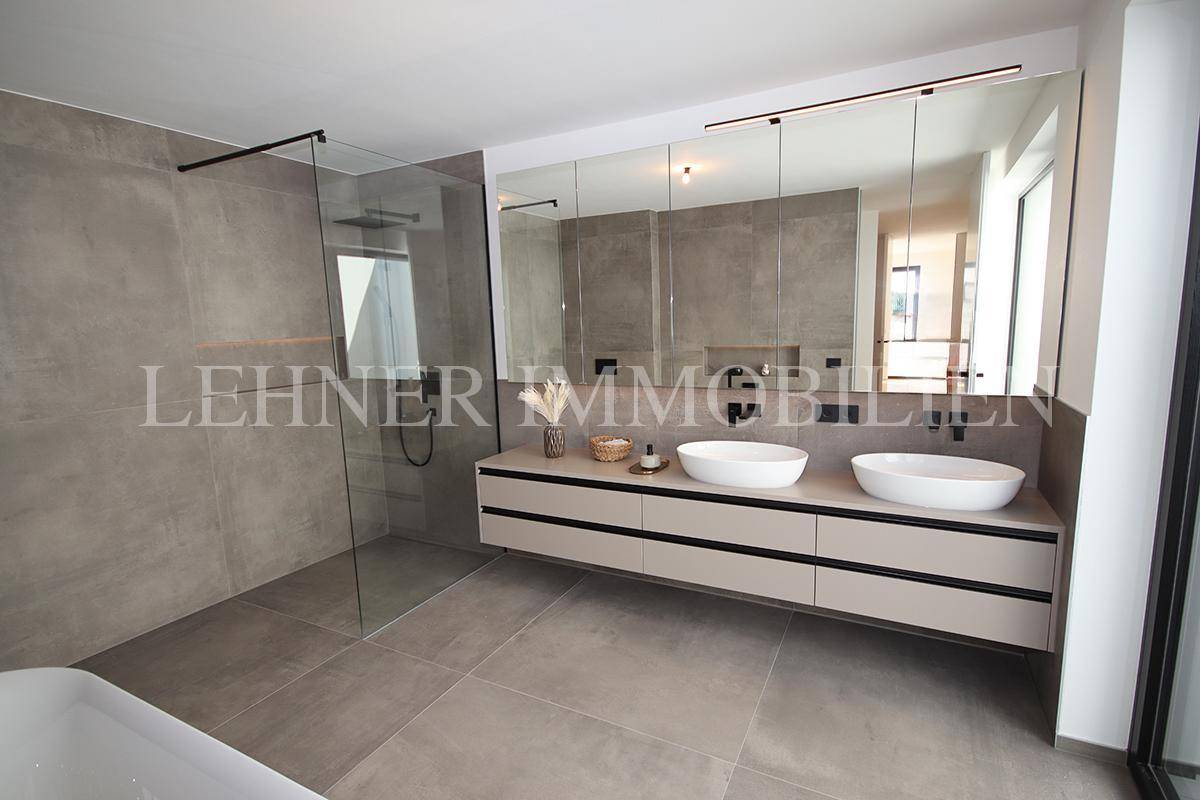 Luxuriöses Badezimmer mit Doppelwaschbecken, großer Dusche und freistehender Badewanne.