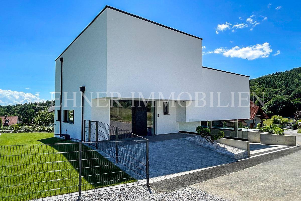Moderne Eingangsfassade der Villa mit gepflastertem Vorplatz und minimalistischem Design.