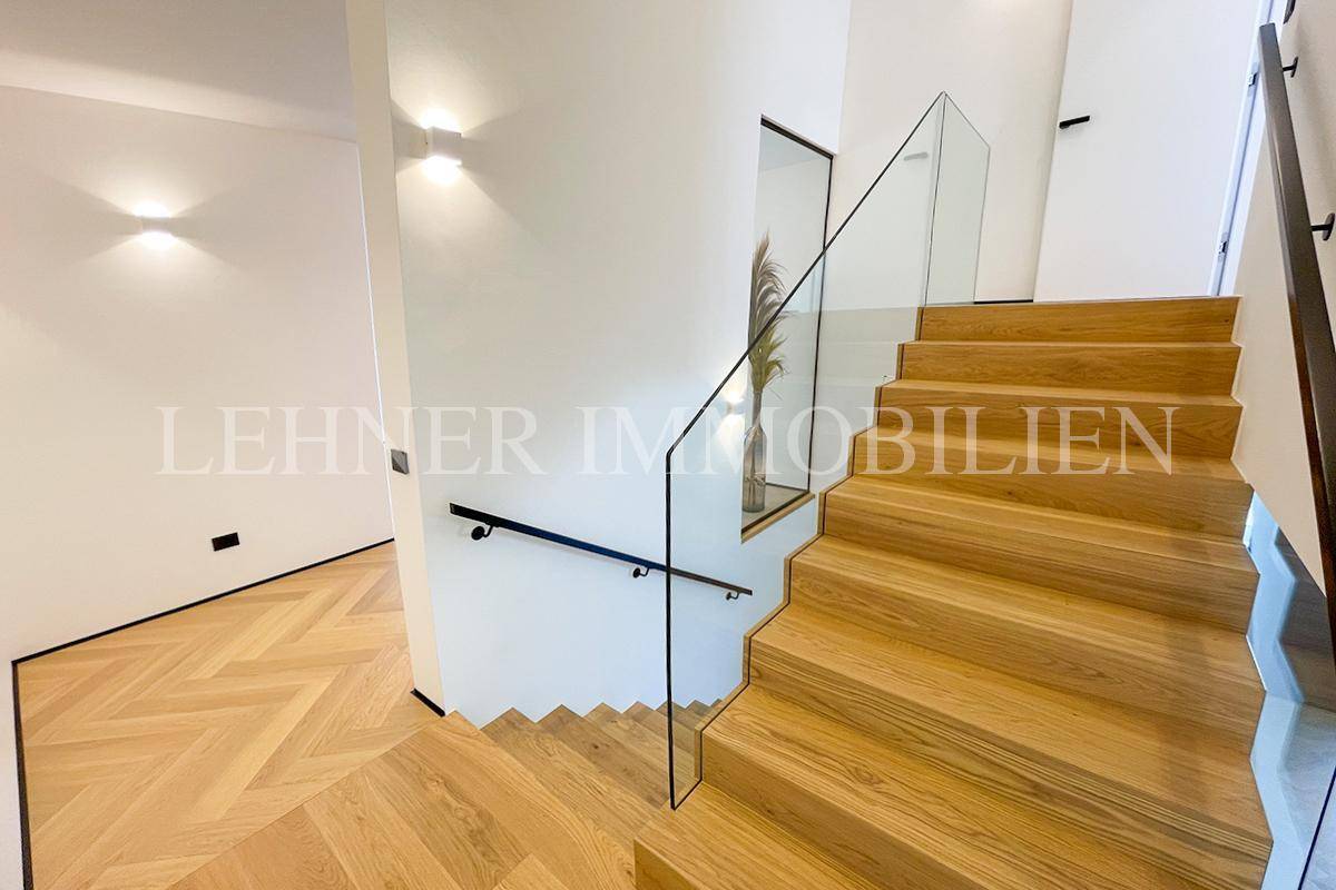 Moderne Holztreppe mit Glasgeländer und minimalistischer Beleuchtung.